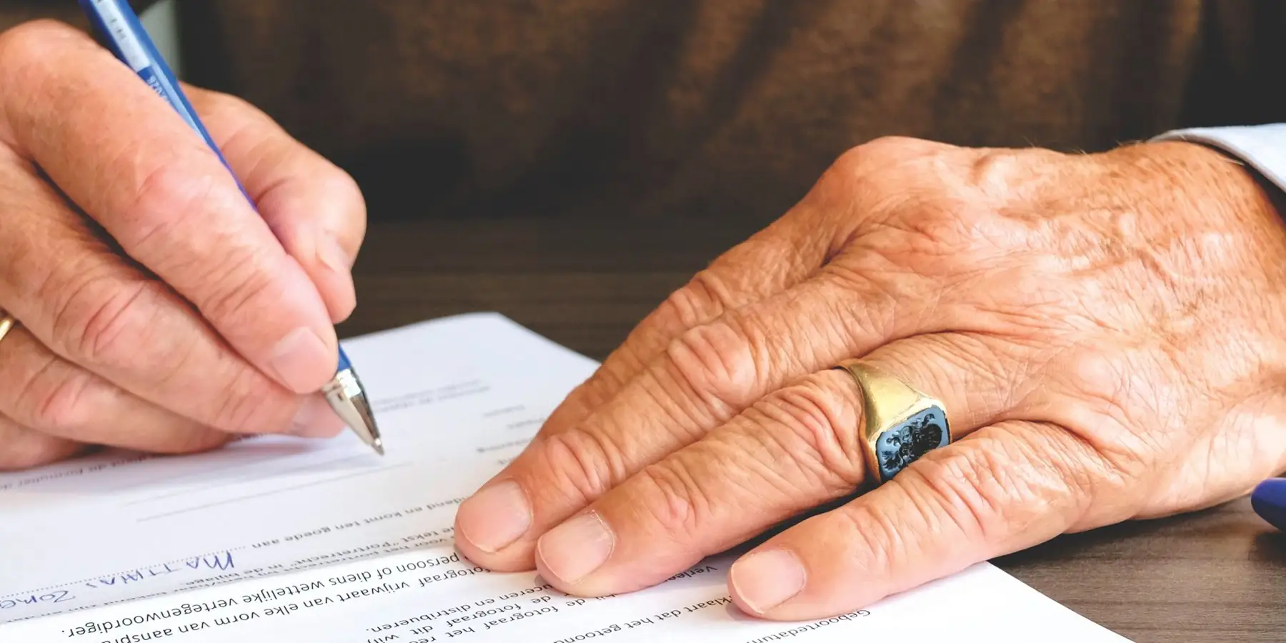 Manos de una persona mayor firmando un documento