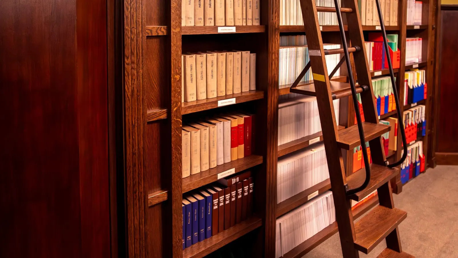 Biblioteca de madera con escalera y libros de derecho